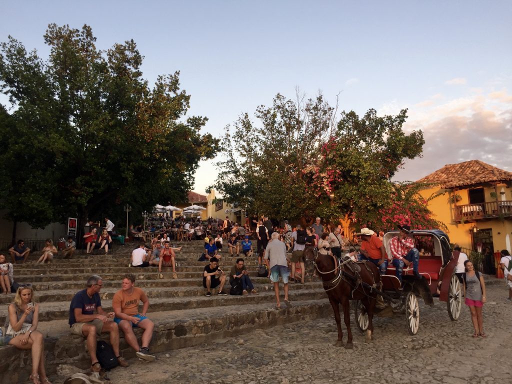 people sitting on the stairs on the main square in Trinidad, Cuba.