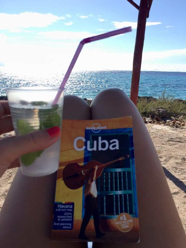 A mojito and a Cuba travel guide at the beach.