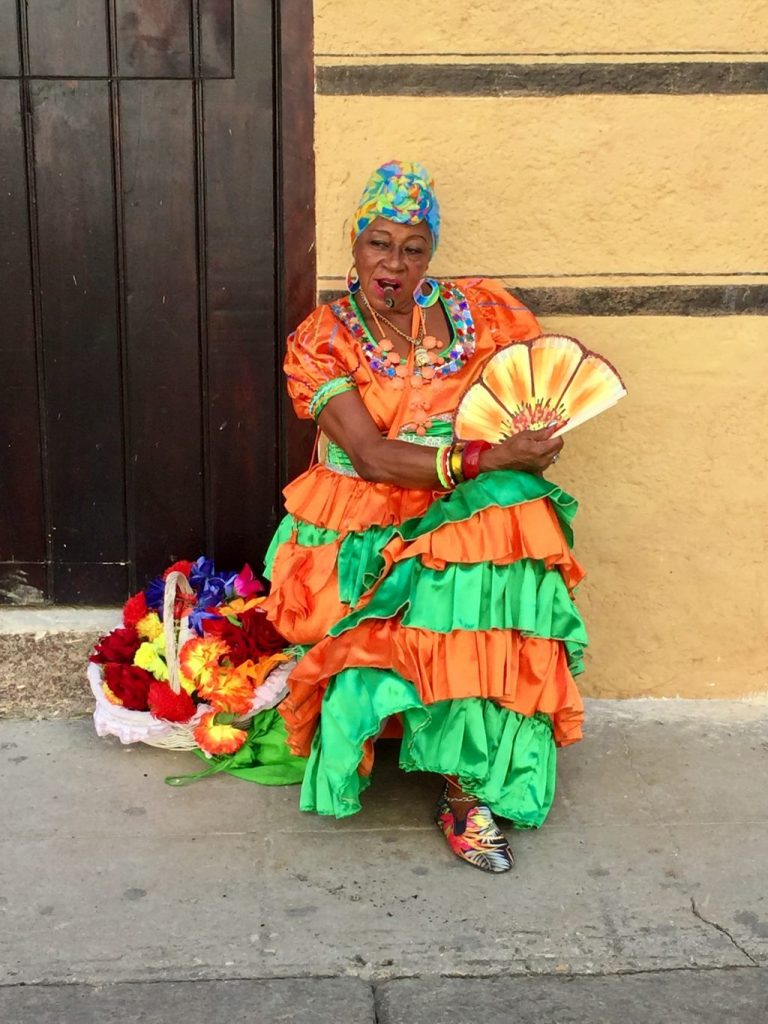 old Cuban lady in a colourful dress smoking a cigar